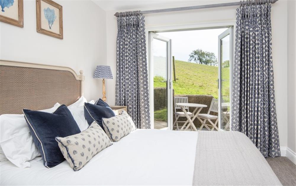 Gorgeous bedroom 1 with a door to the terrace and its own table and chairs at Stancombe Cottage in Sherford