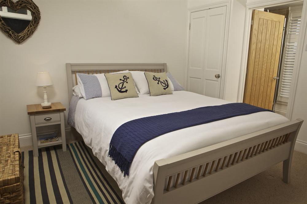 En suite double bedroom with King-size wooden bed at Starfish Cottage in 40 Crowthers Hill, Dartmouth