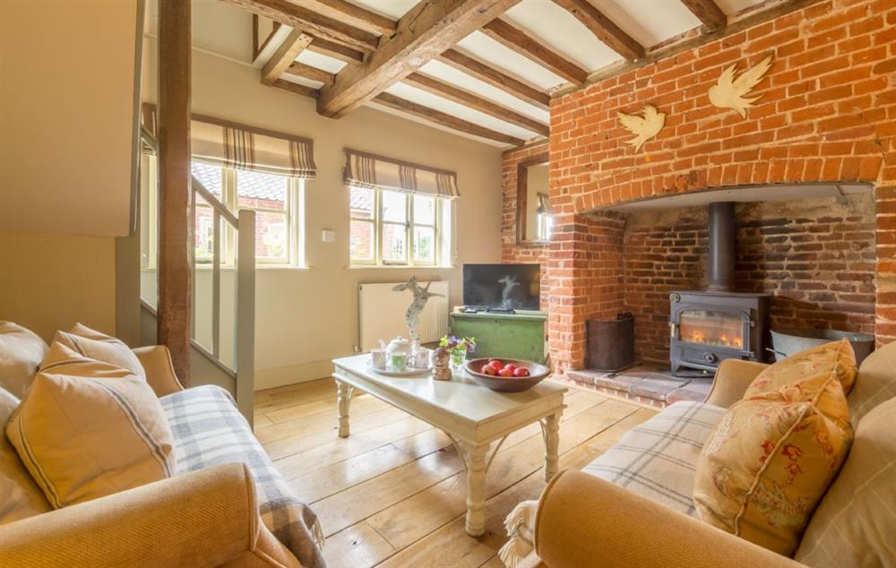 Sitting room with an inglenook fireplace with wood burning stove at Stockmans Cottage, Foulsham