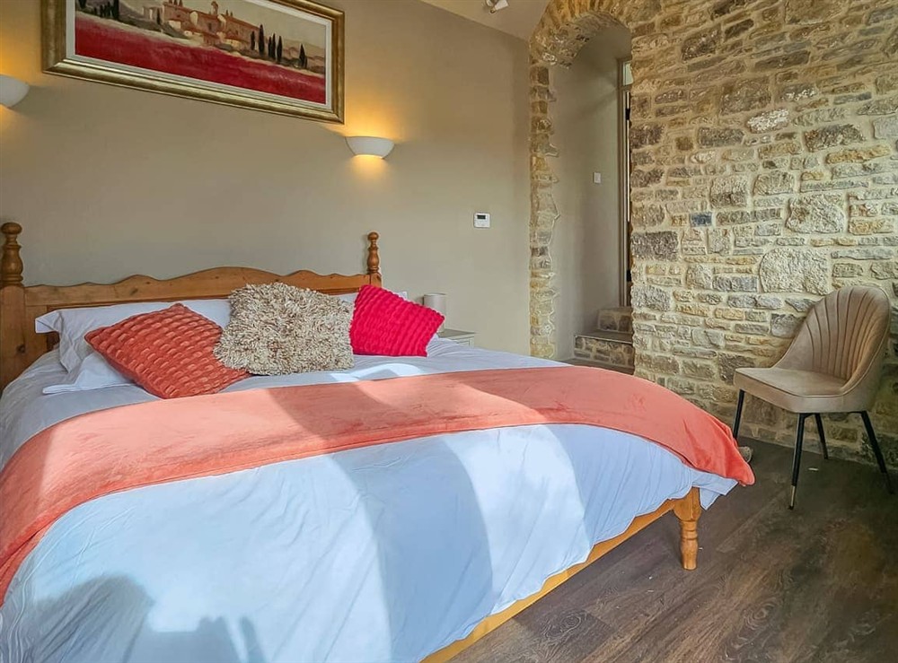 Master bedroom with en-suite 17th century stone wall and beems at Stone Cottage in Maltfield, near Wedmore, Somerset