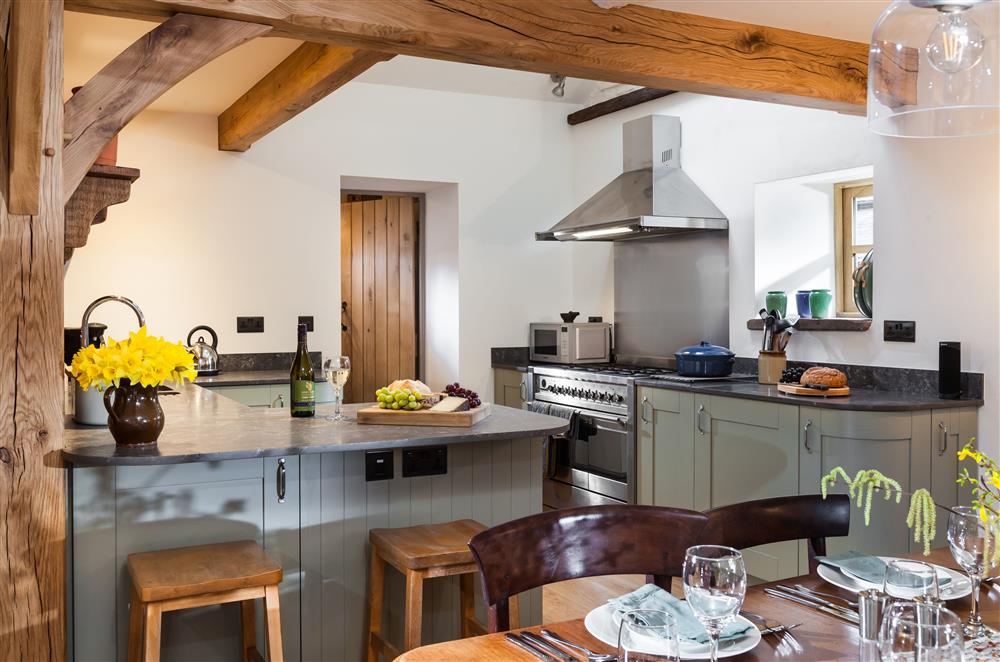 The dining area leading through to the kitchen with exposed beams at Stone House, Leominster