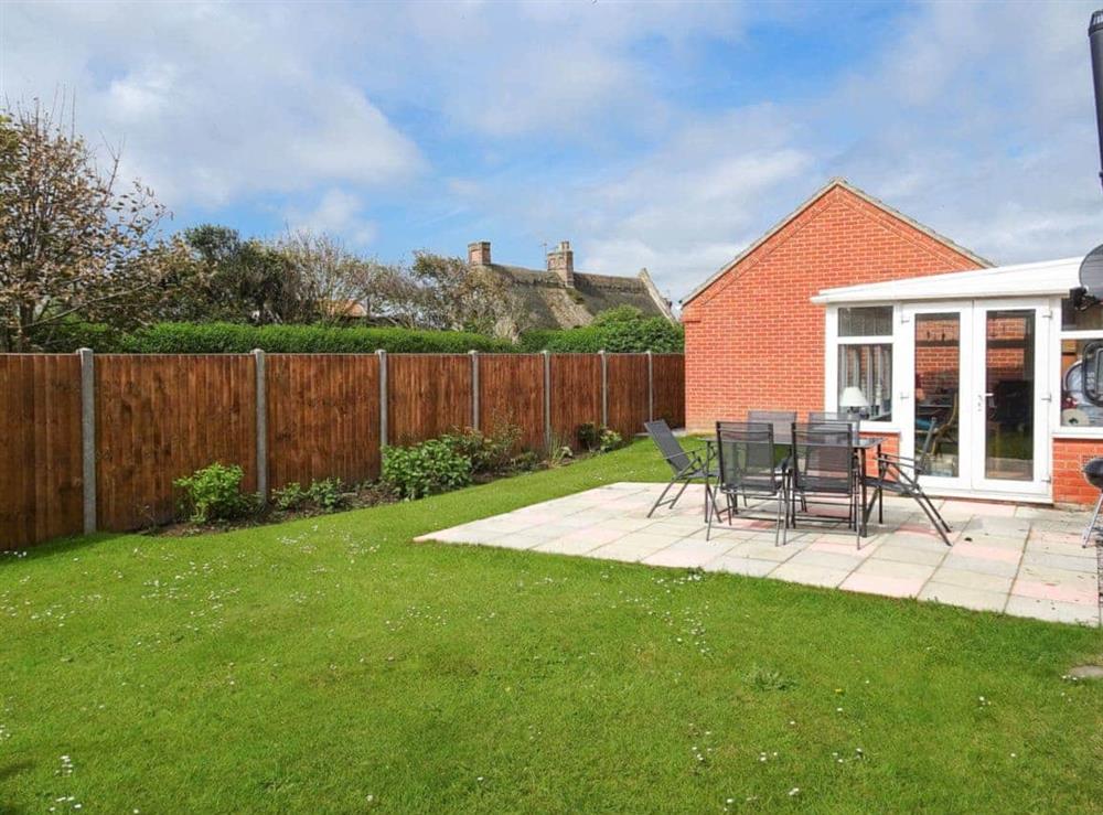 Part-lawned garden with flagged patio and outdoor furniture at Stones Throw in Bacton, Norfolk