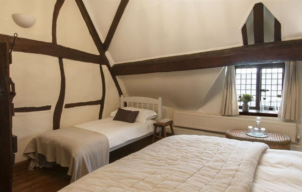 Family bedroom with an A-frame cruck beam and exposed timbers, with a 6’ super-king bed and a 3’ single bed (photo 2)