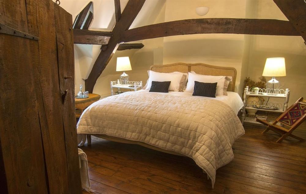 Family bedroom with an A-frame cruck beam and exposed timbers, with a 6’ super-king bed and a 3’ single bed