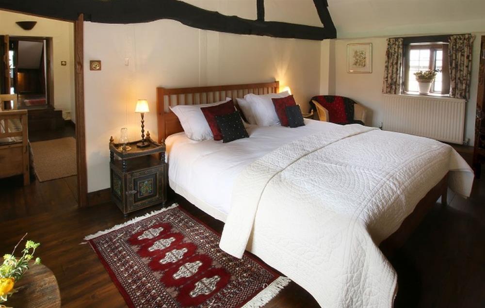 Third bedroom with a 6’ super-king bed, exposed beams and an attractive cruck shaped ceiling at Stourton Manor, Stourton