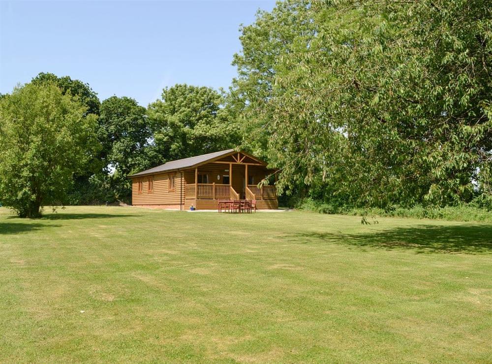 Lodge style holiday home with large lawned garden at Tarkas Holt Log Cabin, 