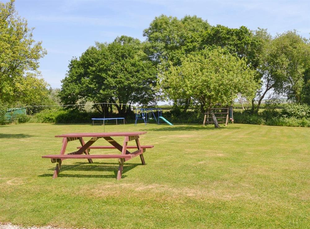 Large lawned garden with children’s play area at Warren Cottage, 