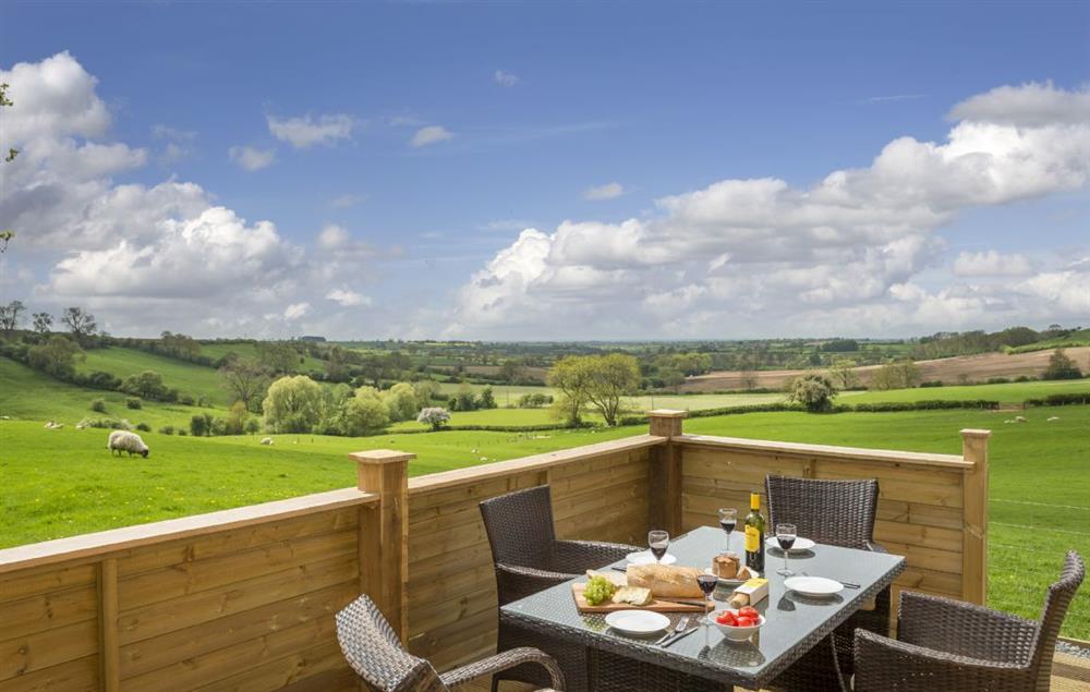 A wooden veranda with garden furniture looks on to open countryside (photo 2) at Strawberry Lodge, Billesdon