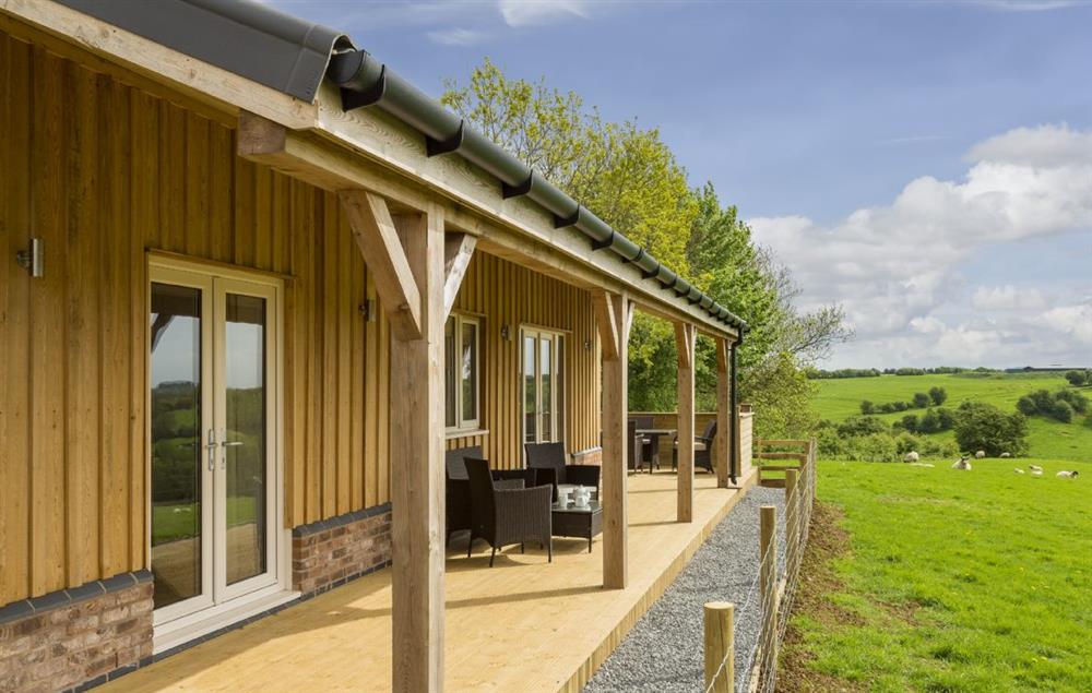 A wooden veranda with garden furniture looks on to open countryside at Strawberry Lodge, Billesdon