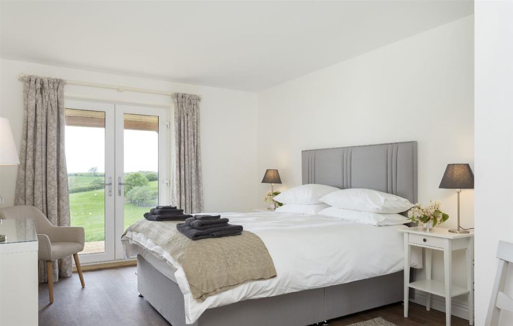 Bedroom with king size bed and en-suite bathroom with shower, and french doors to veranda at Strawberry Lodge, Billesdon