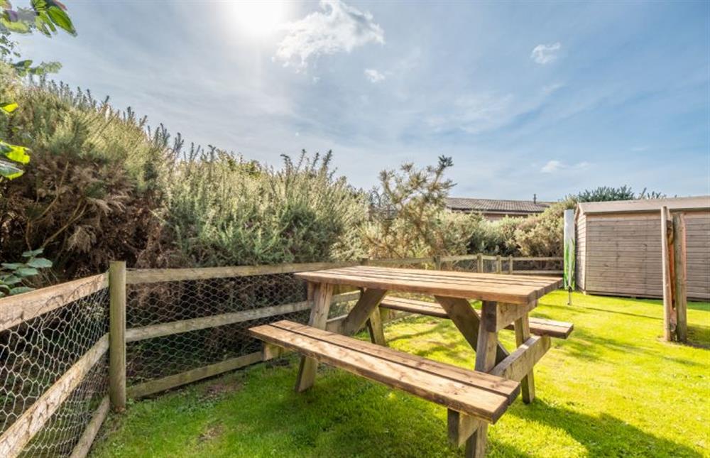 Behind the lodge is a garden area with a picnic table with bench seating at Suffolk Barn, Kelling near Holt