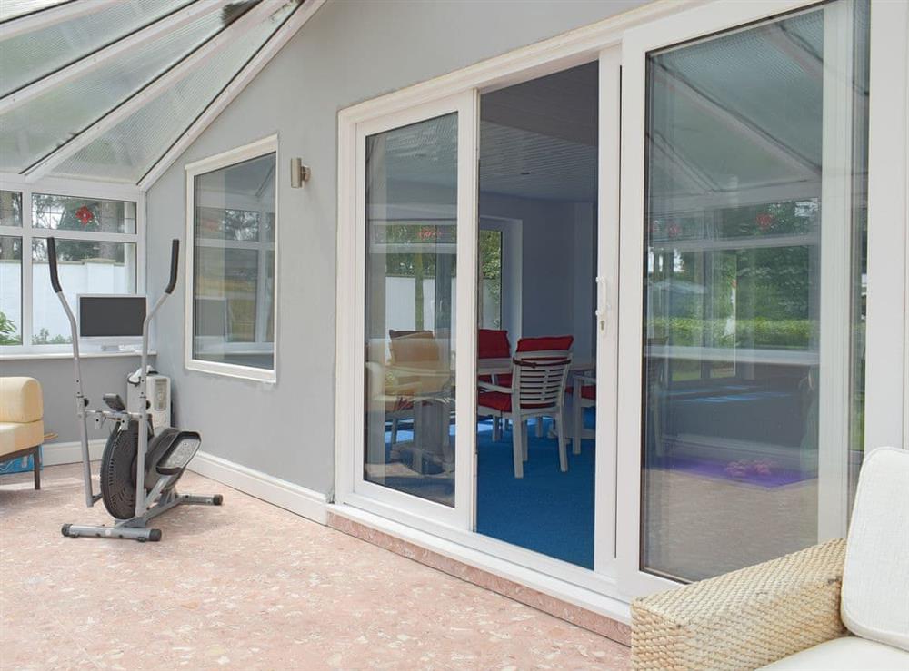 Patio doors connect the swimming pool to the conservatory at Sunset Cottage in Halsall, near Ormskirk, Lancashire