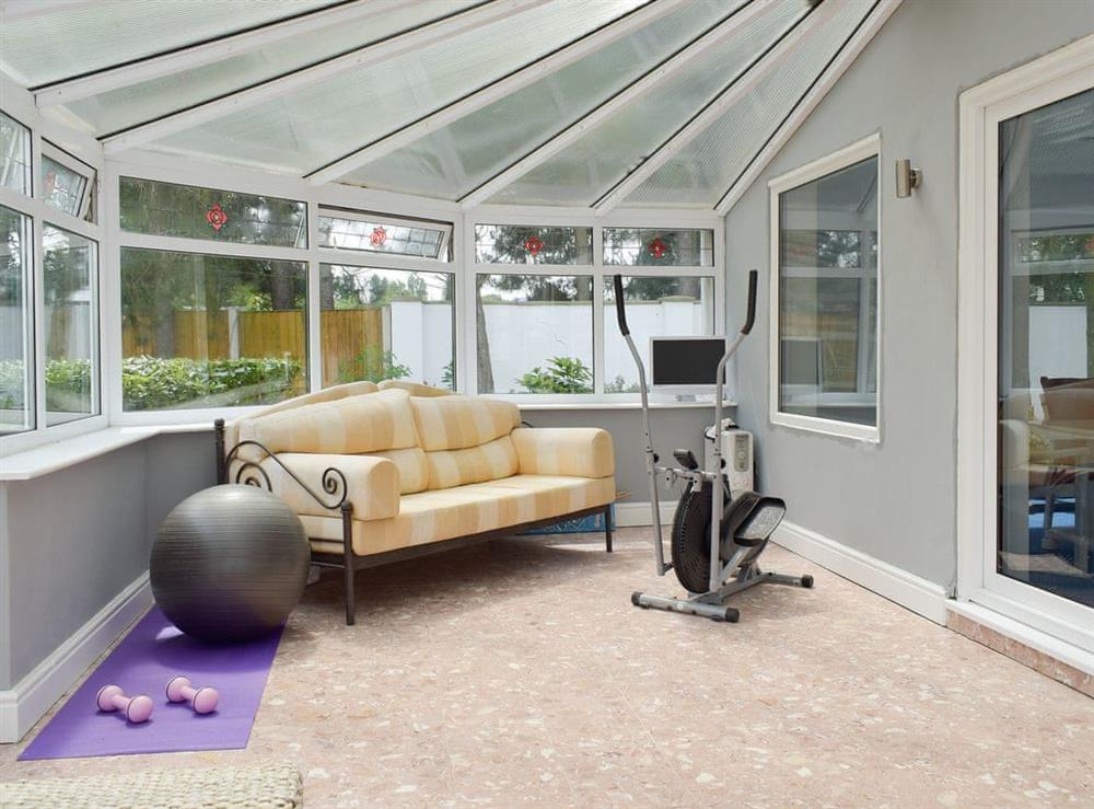 Spacious conservatory with seating and gym equipment at Sunset Cottage in Halsall, near Ormskirk, Lancashire