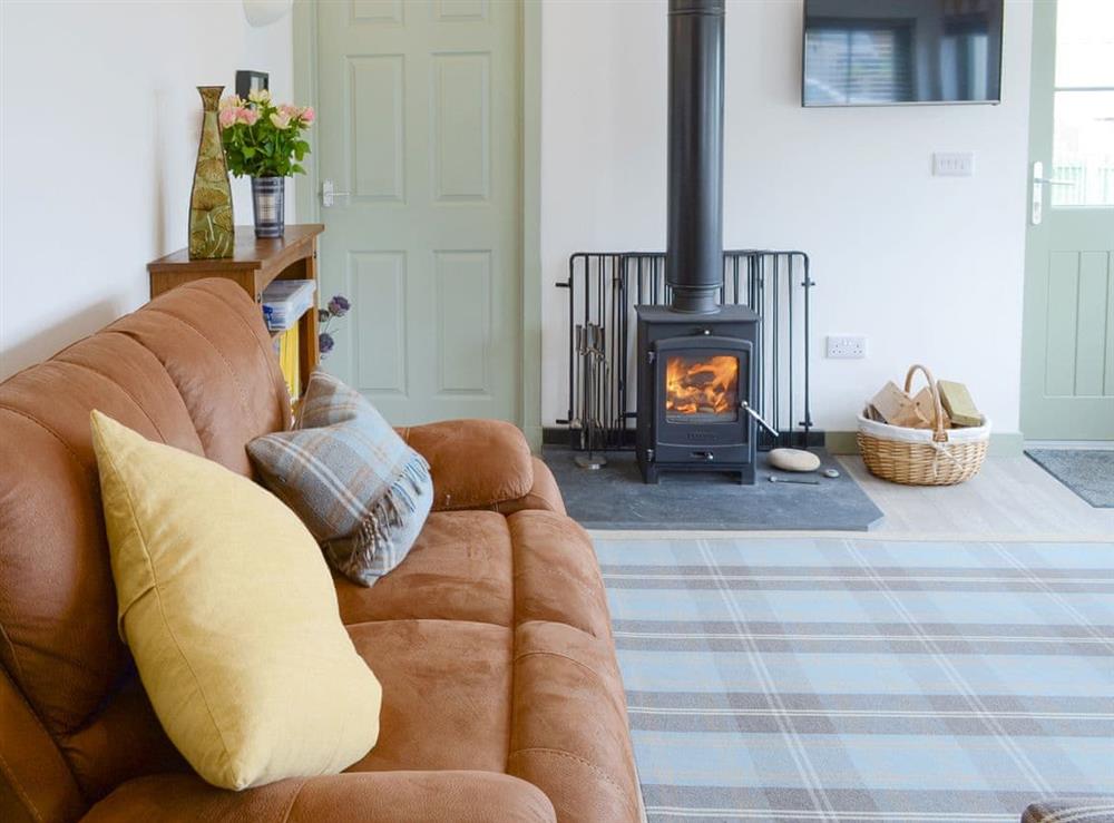 Welcoming living area with wood burner at Sunset Cottage in Portmahomack, near Tain, Ross-Shire