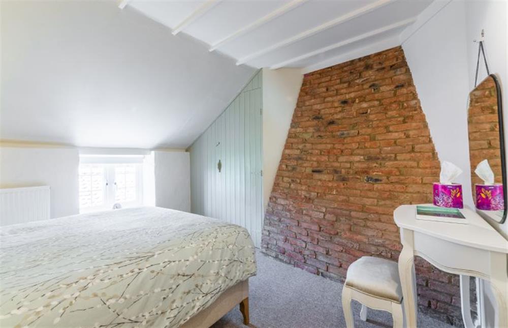 First floor:  Double bedroom with feature exposed brick wall at Swift Cottage, Dersingham near Kings Lynn