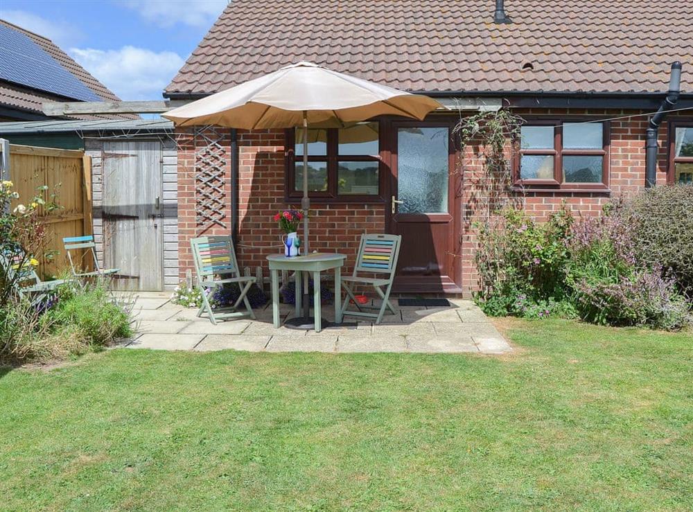 Lawned garden with shady patio area at Tamarisk in Walcott, Norfolk