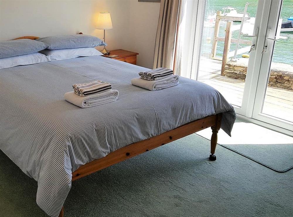 Double bedroom with  French doors leading out onto a small decked patio area with lovely views of the river at Tarquins in Fowey, Cornwall