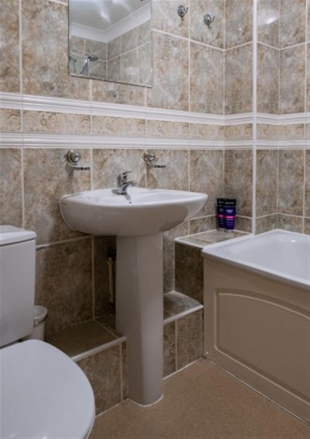 The beige tiling and white bathroom suite compliments each other. at Teylu in Maenporth