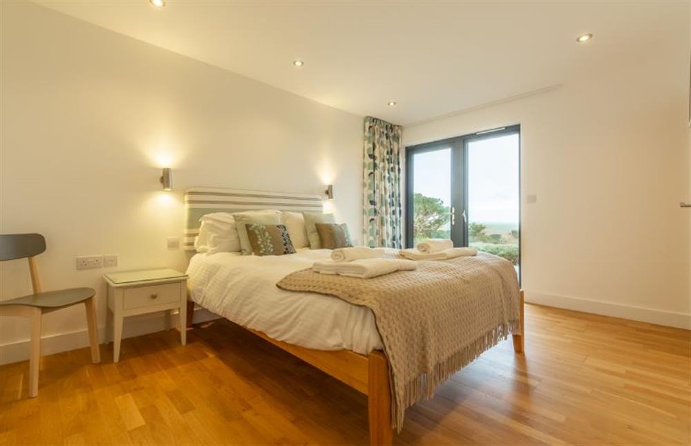 Bedroom one with king-size bed, sea views and french doors to deck at Teyr Mor Cliff, Chapel Porth, St Agnes
