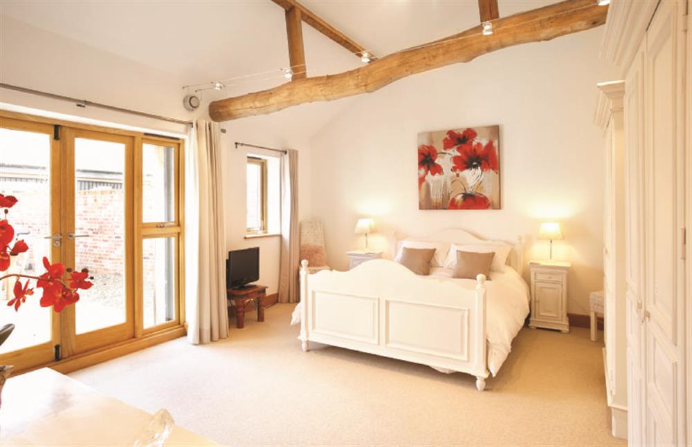 Ground floor: Master bedroom with  super-king bed and french doors leading to the courtyard at Thatch Barn, Burlingham Green near Norwich