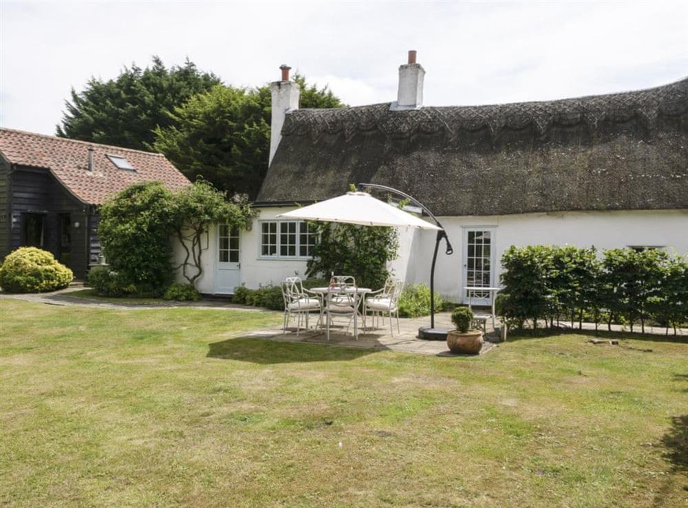 Enclosed lawned garden with patio and garden furniture at Thatched Cottage in Sternfield, near Aldeburgh, Suffolk