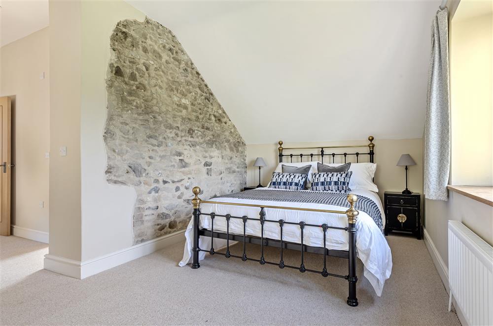 The exposed stone wall adds a characterful touch to bedroom one at The Barn, Chard, West Dorset