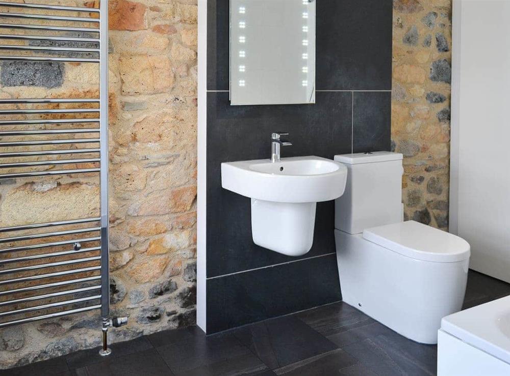 Contemporary design bathroom with exposed stone feature wall at The Barn in St Austell, Cornwall