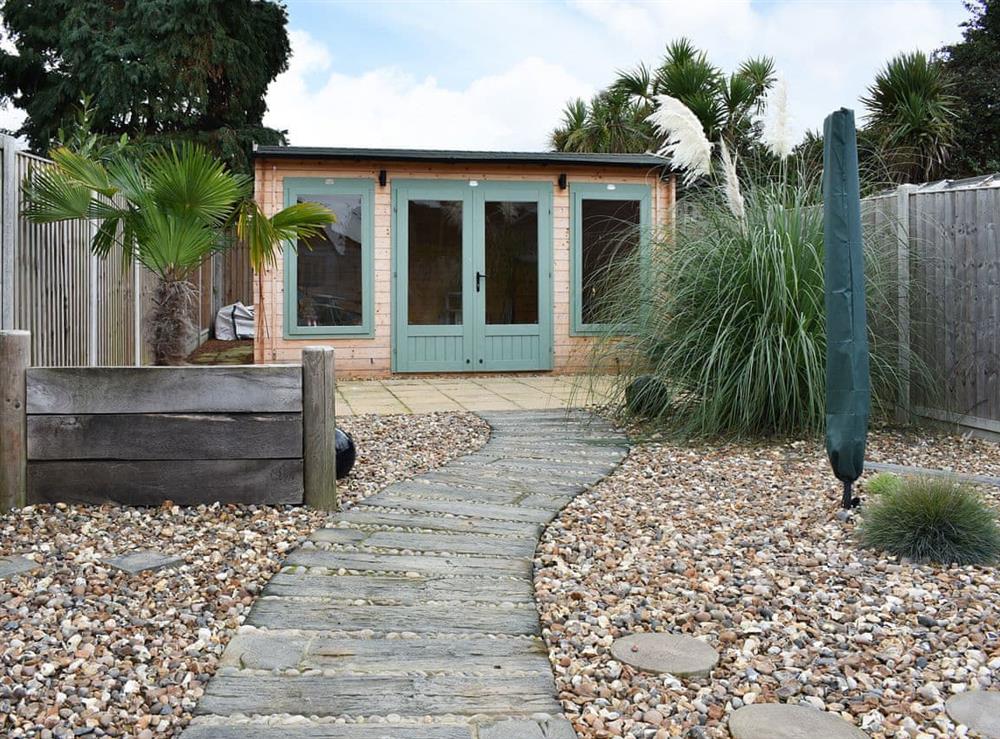 Garden with winding wooden path leading to a garden room at The Beach House in Holland-on-Sea, Essex