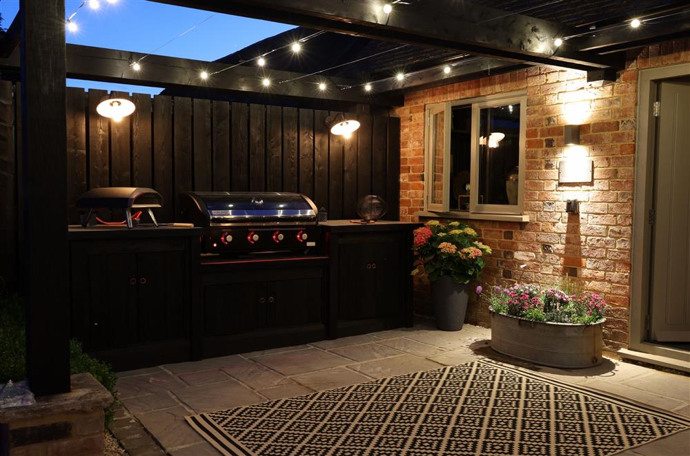 The outdoor kitchen is lit with cosy lighting in the evening  at The Big Barn, Walton, Near Stratford-upon-Avon