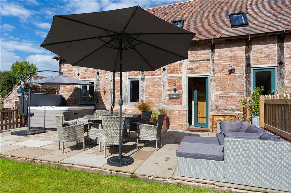 Sun-kissed lawned garden with a hot tub and comfortable rattan garden furniture at The Byre, Bridgnorth