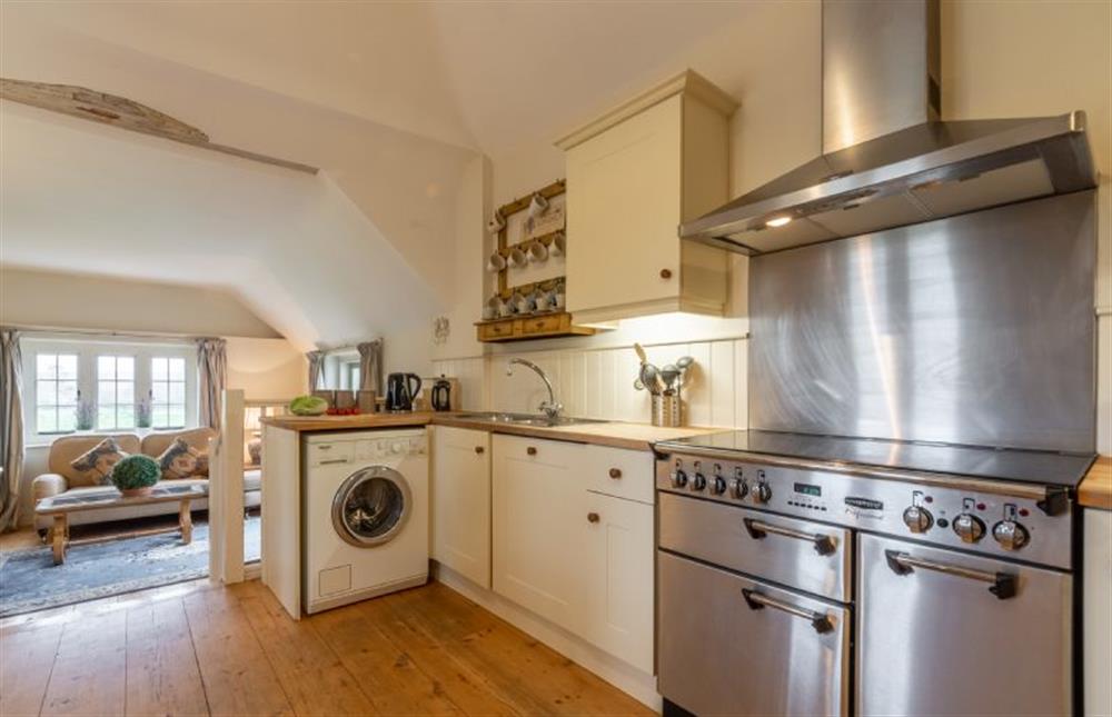 Open-plan kitchen area with washing machine, range cooker and leading to sitting area at The Cartlodge, Higham