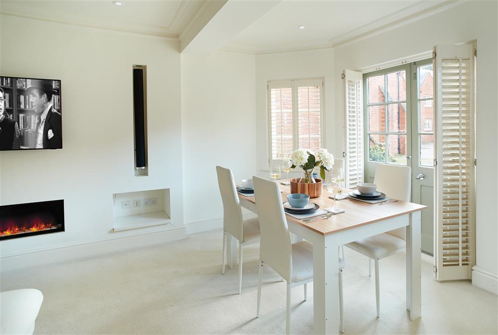 Dining area with table and seating for four guests and views through the french doors to the patio and lawn