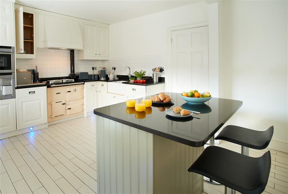 Open-plan kitchen with breakfast bar/island unit and four stools at The Chapel House, Arley