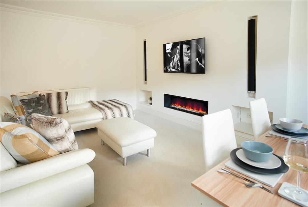 Open-plan sitting room with modern feature gas fire and Smart television at The Chapel House, Arley