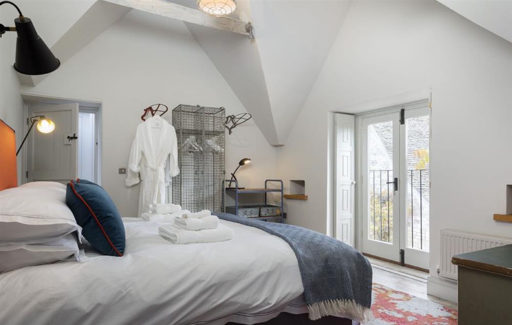 Bedroom two with a super-king size zip and link bed and Juliet balcony at The Coach House and Stables at The Lammas, Minchinhampton