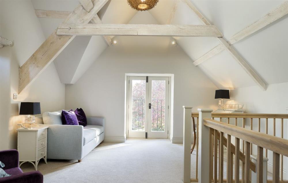 First floor day room with double doors and window with balcony railings looking out onto the garden at The Coach House and Stables at The Lammas, Minchinhampton