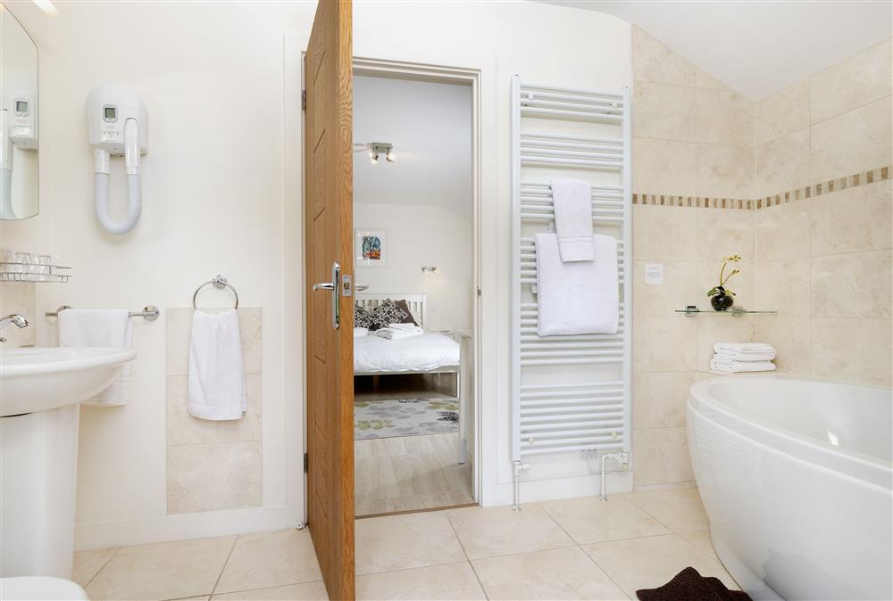 En-suite bathroom with corner bath and hand-held shower attachment at The Coach House at The Old Rectory, Leominster