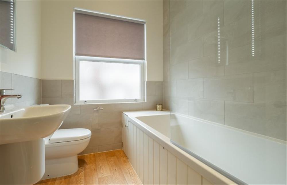 First floor: Bathroom with a bath and shower over, wash basin and WC at The Coach House, Cromer