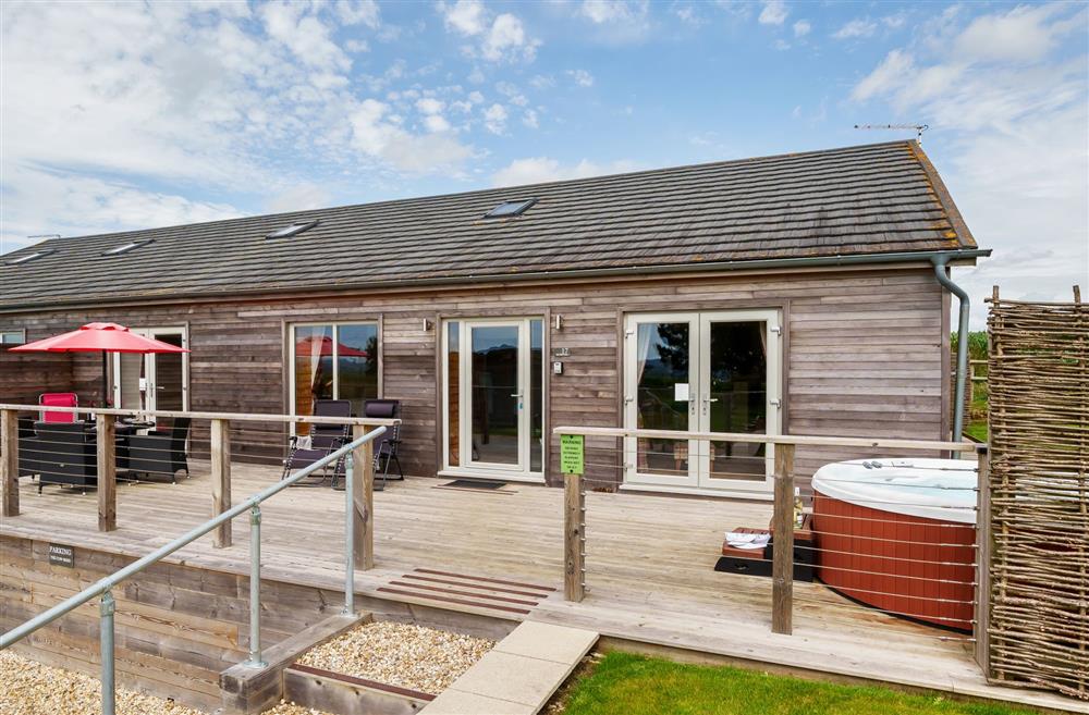The sun deck with garden furniture seating four guests and a hot tub at The Cow Shed, Sherborne