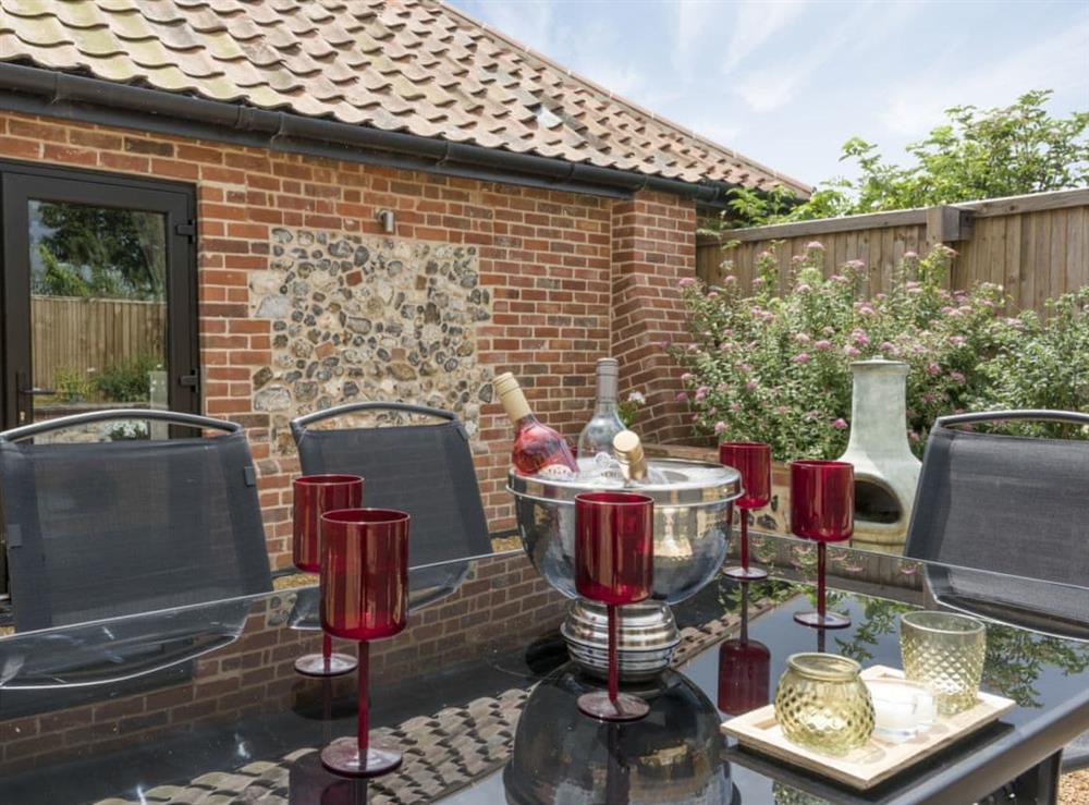 Enclosed patio garden with sitting-out area and garden furniture at The Cowshed in Horning, near Wroxham, Norfolk