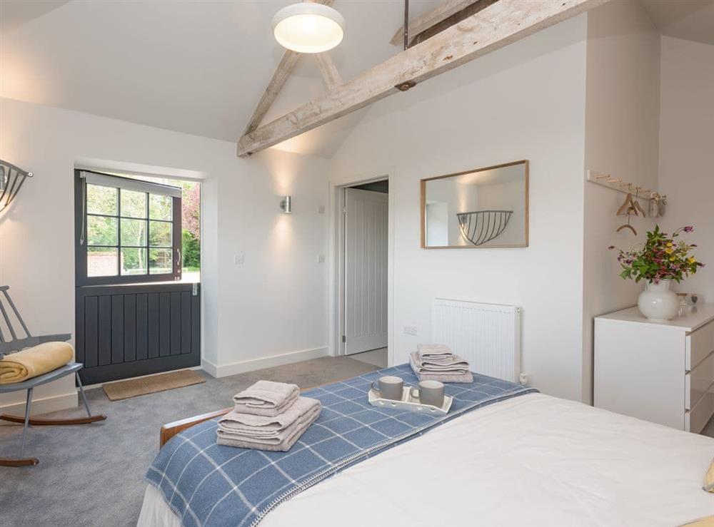 Light and airy en-suite double bedroom with door to enclosed patio at The Cowshed in Reepham, Norfolk