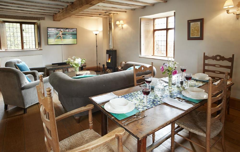 Open plan sitting room with wood burning stove, kitchen and dining area with large dining table seating four
