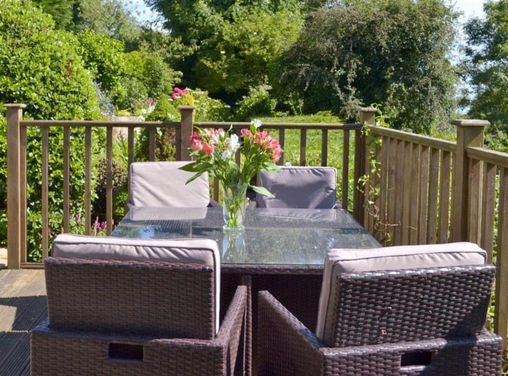Outdoor furniture on decked area overlooking garden at The Garden Room in Brixham, Devon