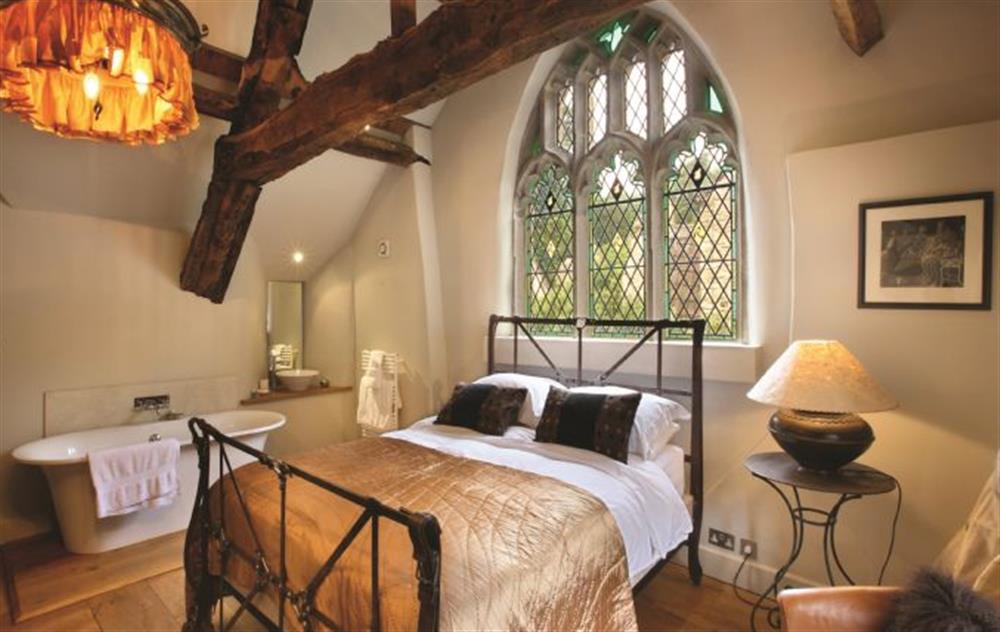 Master bedroom with king-size bed and free standing bath and wash hand basin at The Gates, Castle Combe
