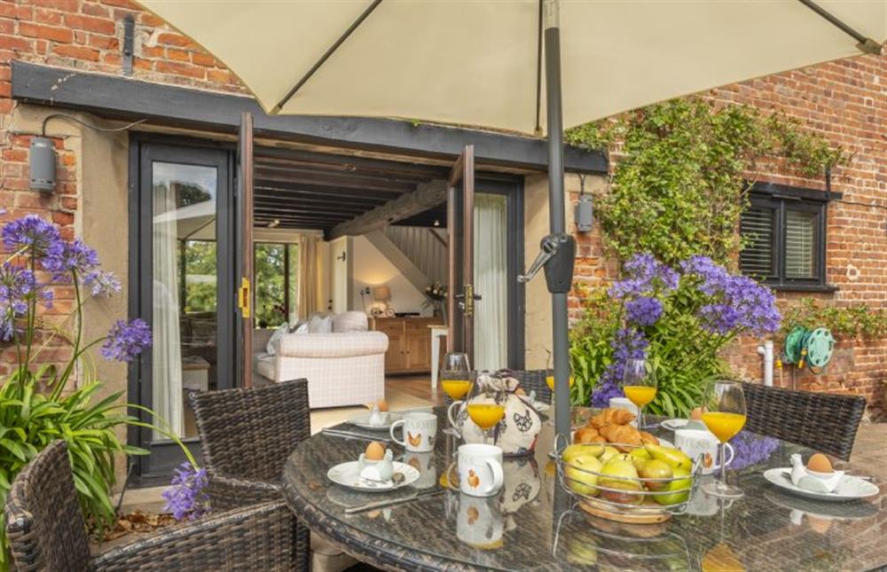 Pretty courtyard garden with dining set and parasol at The Granary, Oulton near Norwich