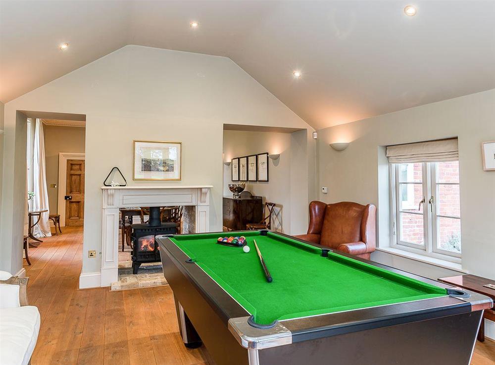 Games room with double-sided wood-burning stove at The Grange Farmhouse in Sculthorpe, Norfolk