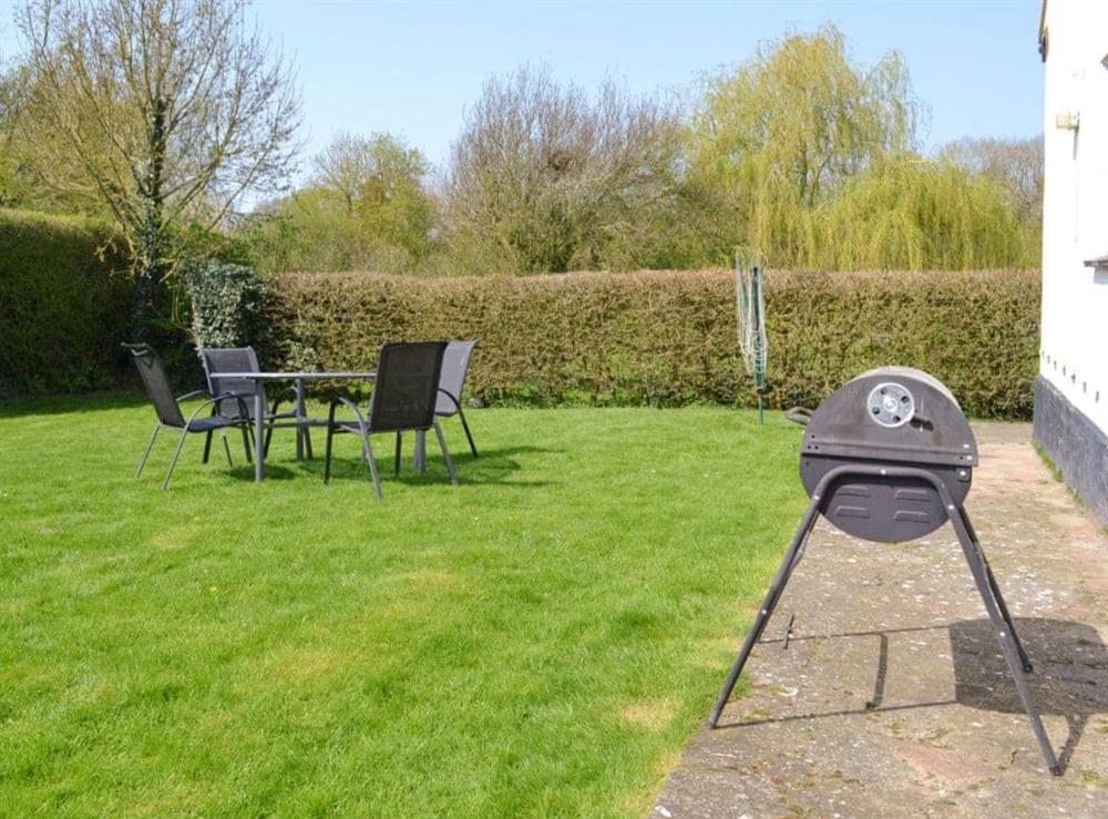 Lawned garden with outdoor furniture and BBQ at The Lodge in Scarning, near Dereham, Norfolk