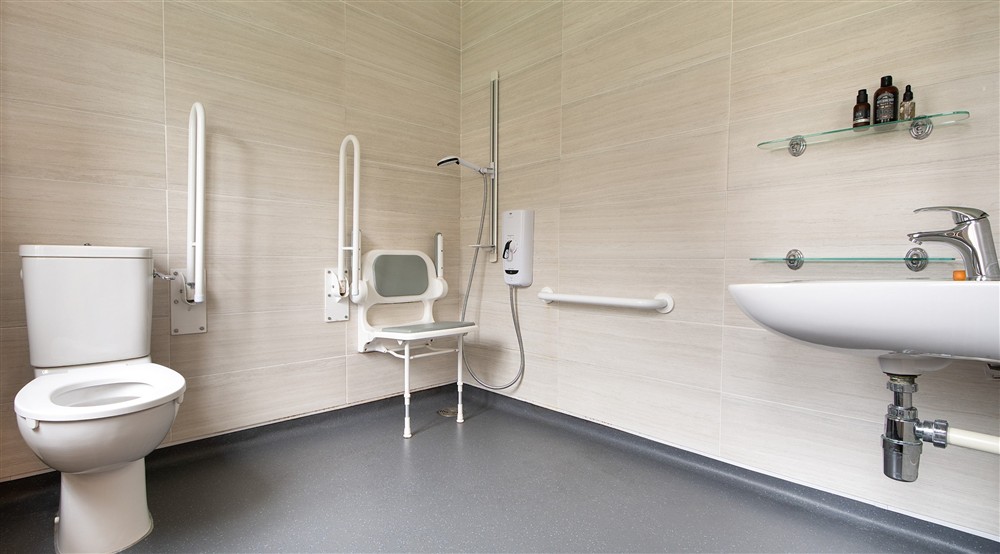 The wet room, with grab rails and hinged shower seat, at The Major's Quarter in Roseland, Cornwall