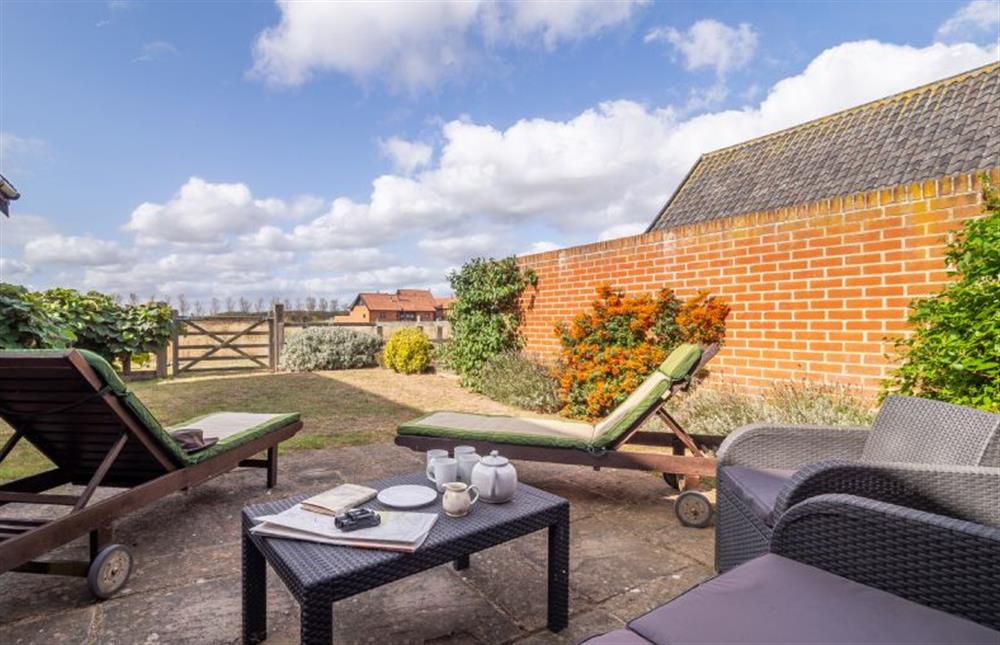 Enclosed garden with seating and sun loungers at The Meadows Dairy, Bawdsey