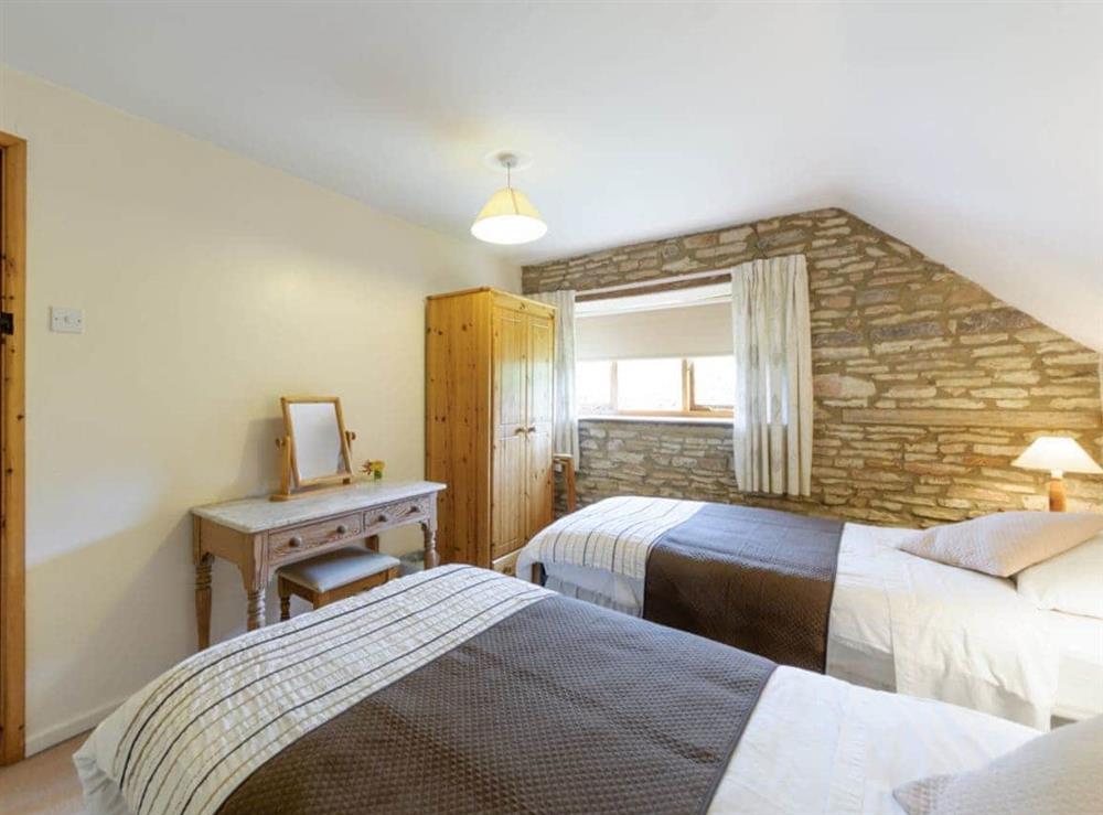 Twin bedroom with exposed stone feature wall at The Mill House in Lea, near Ross-on-Wye, Herefordshire